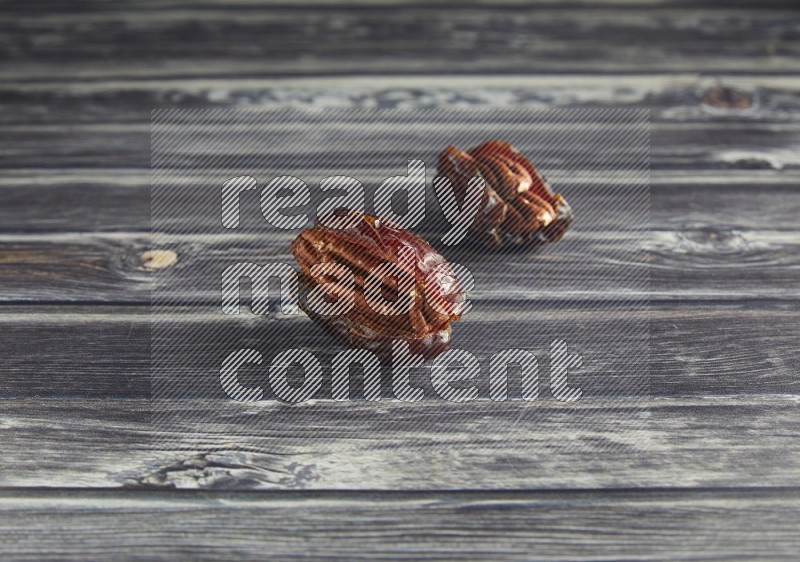 two pecan stuffed madjoul date on a wooden grey background