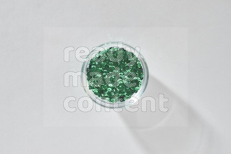 Colored flat sequins in a glass bowl on grey background