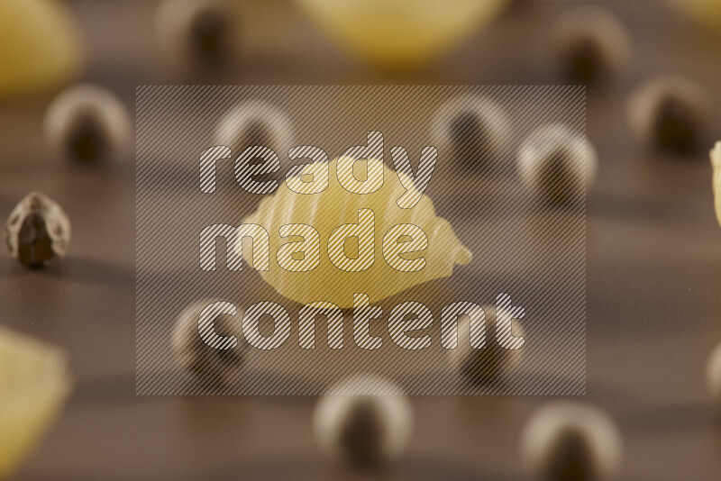 Raw pasta with different ingredients such as cherry tomatoes, garlic, onions, red chilis, black pepper, white pepper, bay laurel leaves, rosemary and cardamom on beige background