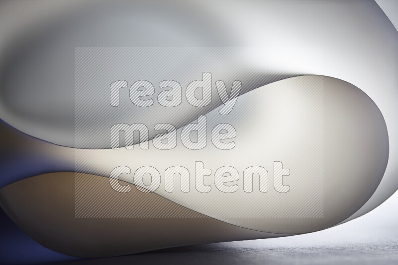 An abstract art piece displaying smooth curves in grey gradients created by colored light