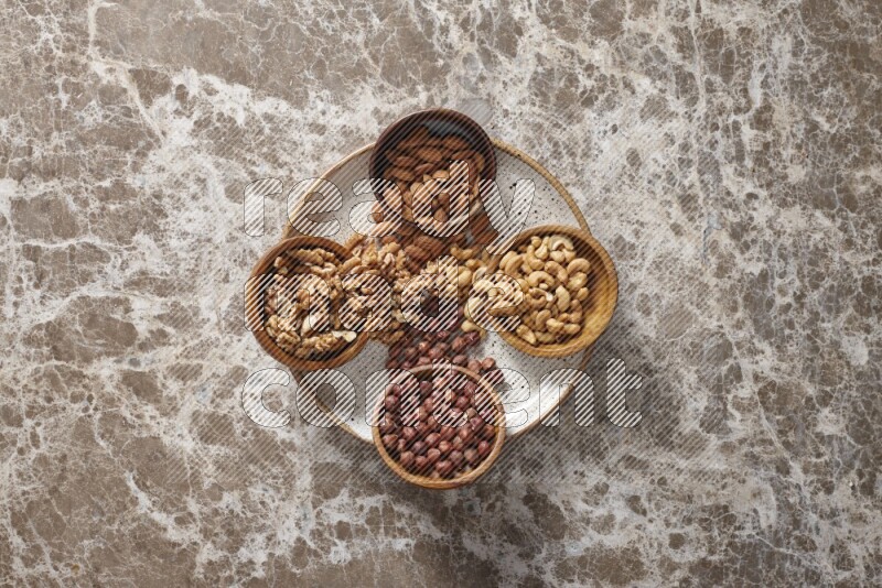Nuts in pottery plates and wooden bowls in a light setup