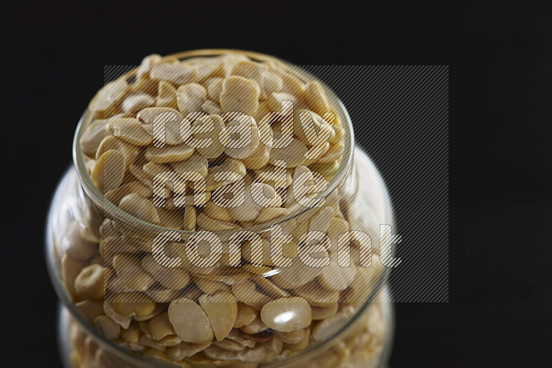 Crushed beans in a glass jar on black background