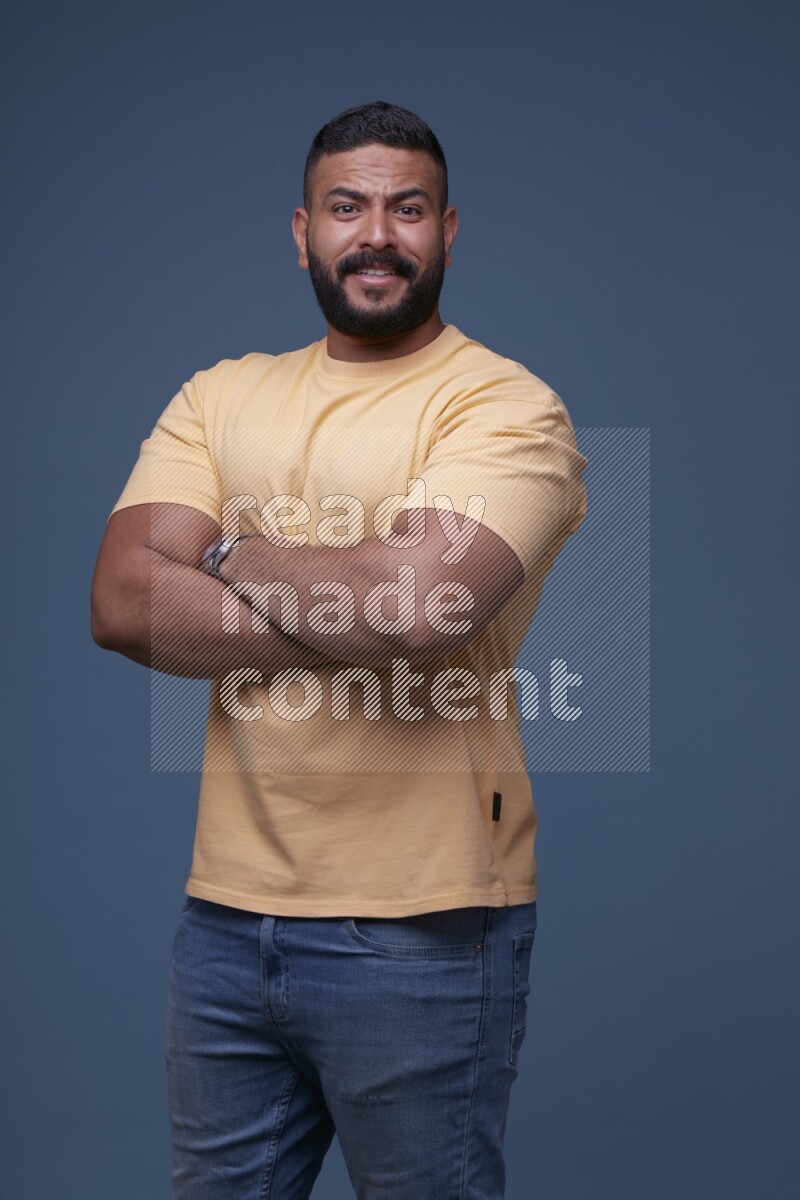 A man posing in a blue background wearing a yellow shirt