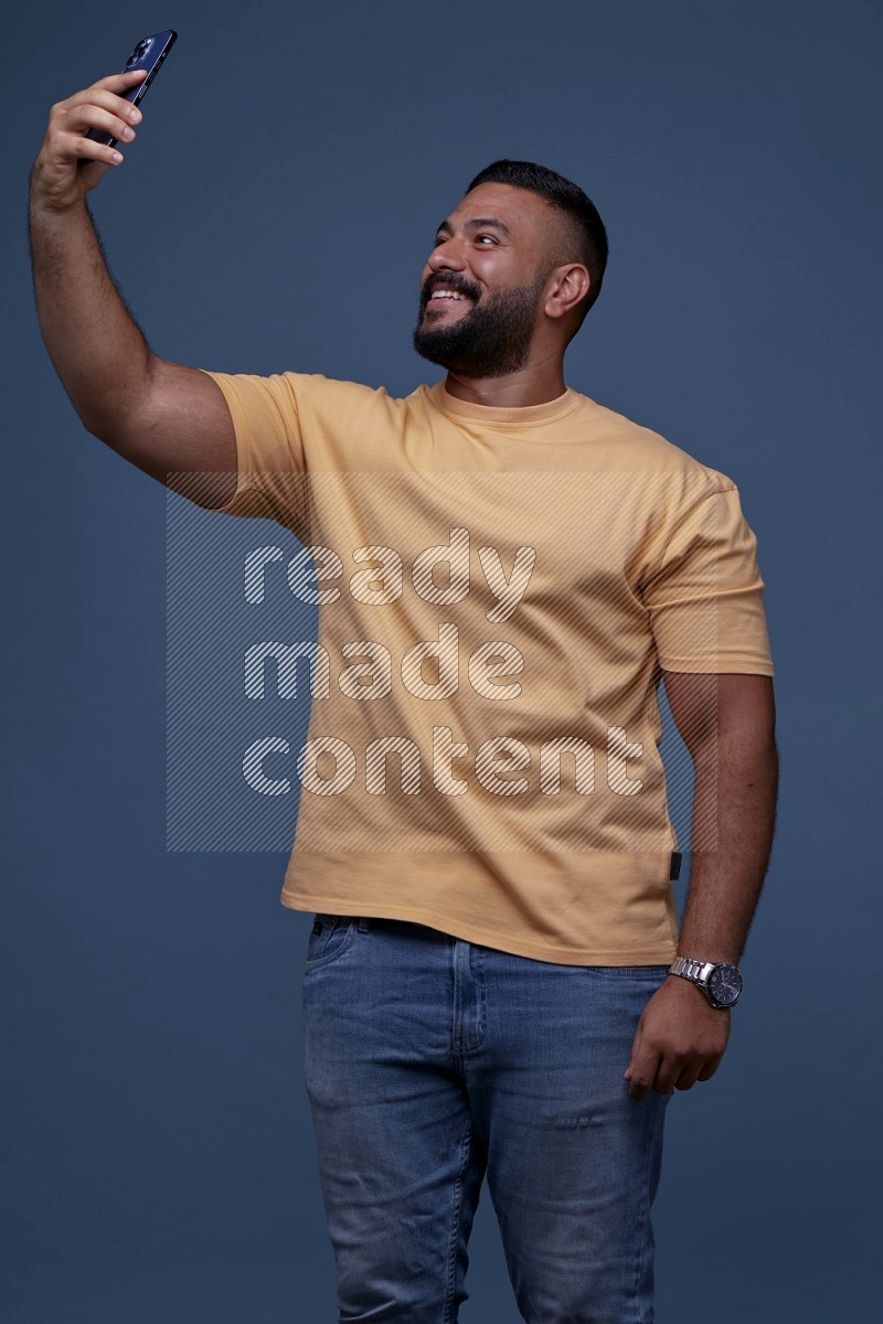 A man Taking A Selfie on Blue Background wearing Orange T-shirt