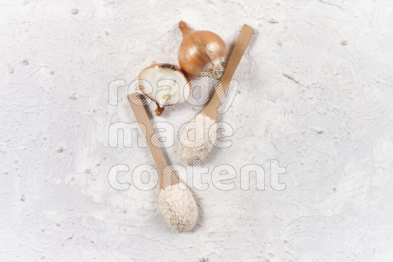 Two wooden spoons full of onion powder on white background