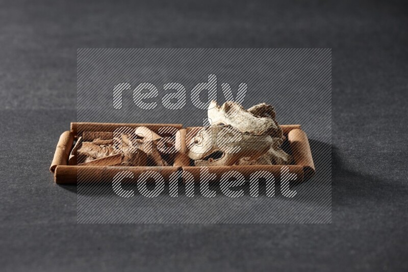 2 squares of cinnamon sticks full of cinnamon and ginger on black flooring