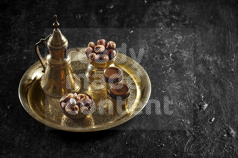 Nuts with dates and a drink on a metal tray in a dark setup