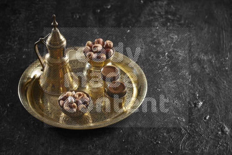 Nuts with dates and a drink on a metal tray in a dark setup