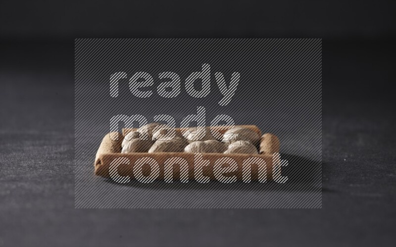 A single square of cinnamon sticks full of nutmeg on black flooring