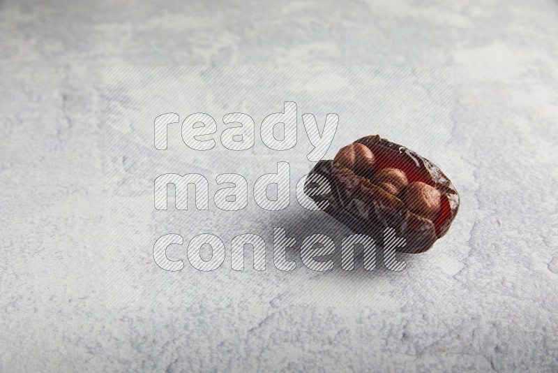hazelnuts stuffed madjoul date on a light grey background