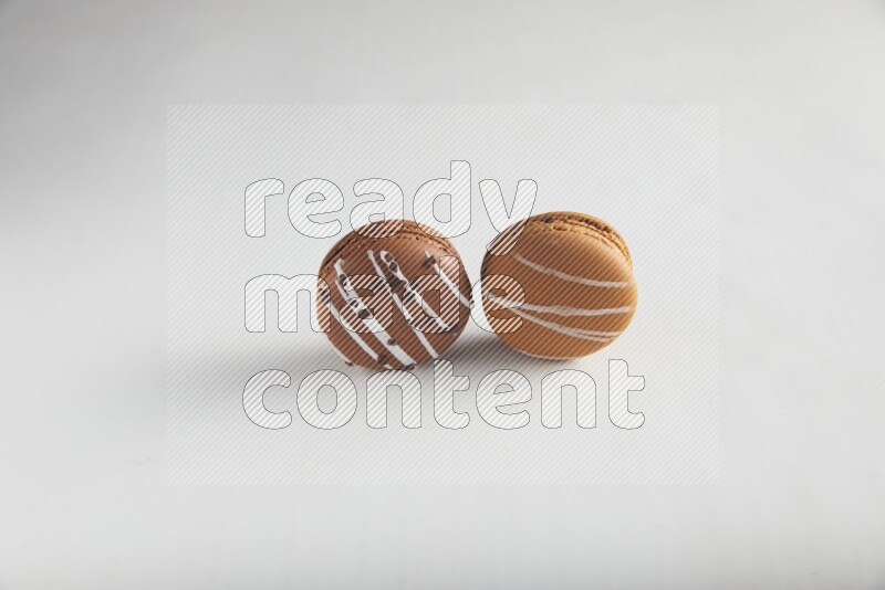 45º Shot of of two assorted Brown Irish Cream, and Brown white Chocolate Caramel macarons on white background