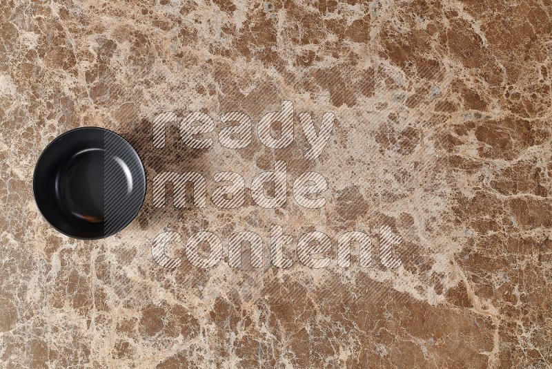 Top View Shot Of A Black Ceramic Bowl On beige Marble Flooring
