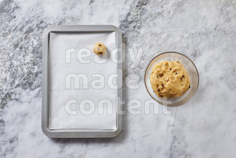 Cookies step by step with its ingredient, flour, butter, brown sugar, egg, vanilla extract, white sugar, chocolate chips and baking soda on grey marble background
