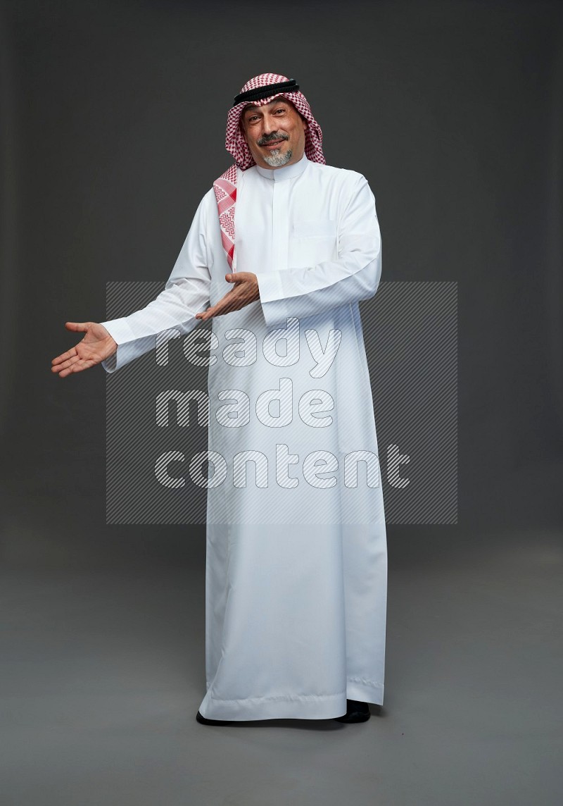 Saudi man with shomag Standing Interacting with the camera on gray background