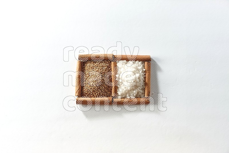 2 squares of cinnamon sticks full of mustard seeds and white salt on white flooring