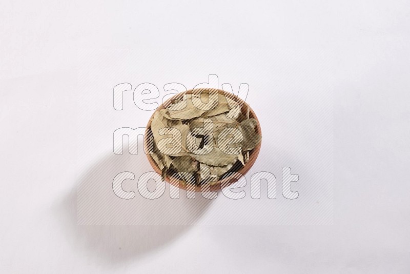 A wooden bowl filled with dried bay leaves on white flooring in different angles