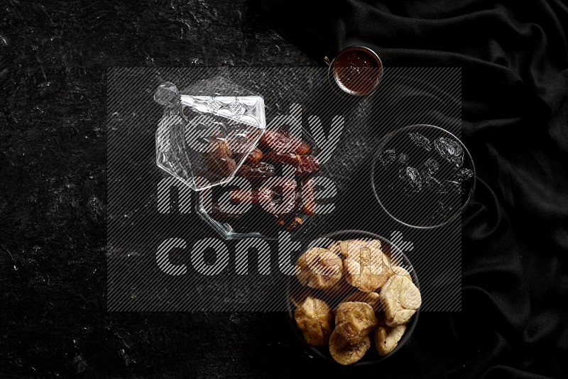 Dates in glass bowl with coffee and dried fruits in a dark setup