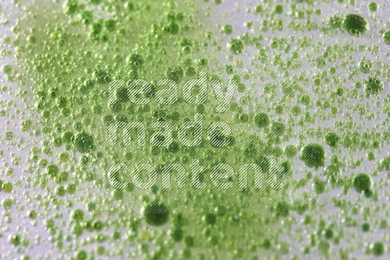لقطات مقربة لقطرات ألوان مائية خضراء على سطح الزيت على خلفية بيضاء