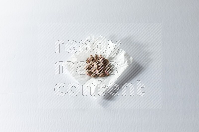 مجموعة من حبوب الفستق المقشر على قطعة من الورق على خلفية بيضاء