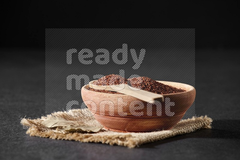 A wooden bowl full of garden cress with wooden spoon full of the seeds on it on burlap fabric on a black flooring in different angles
