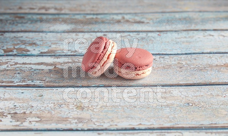 45º Shot of two Pink Litchi Raspberry macarons on light blue wooden background