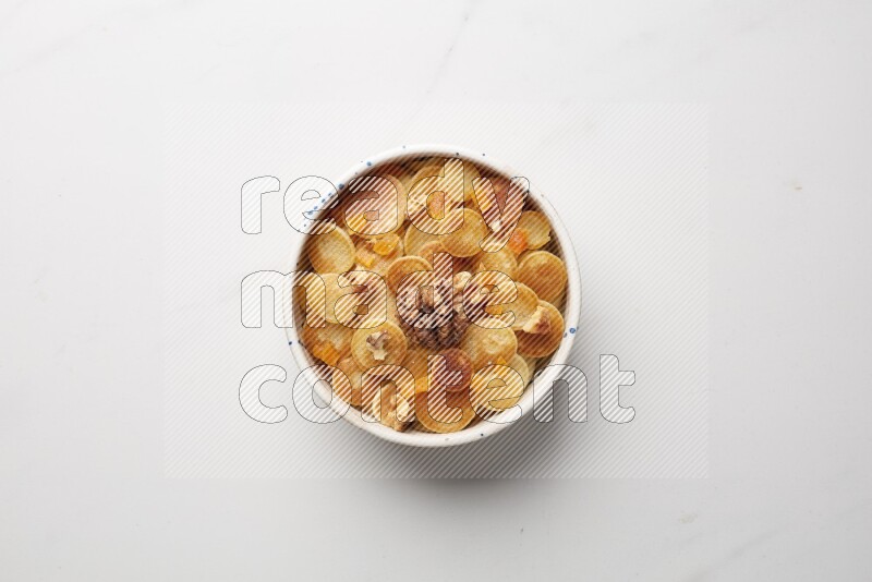 Top-view shot of walnut and apricot cereal pancakes in a round bowl on white background