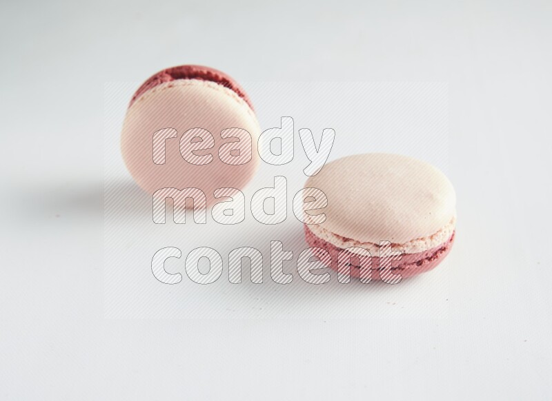 45º Shot of two Pink Litchi Raspberry macarons on white background