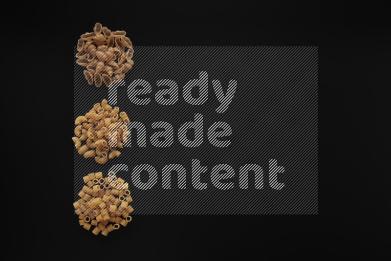Different pasta types in 3 bunches on black background