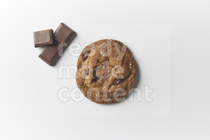 A single chocolate chips cookie with chocolate beside it on a white background