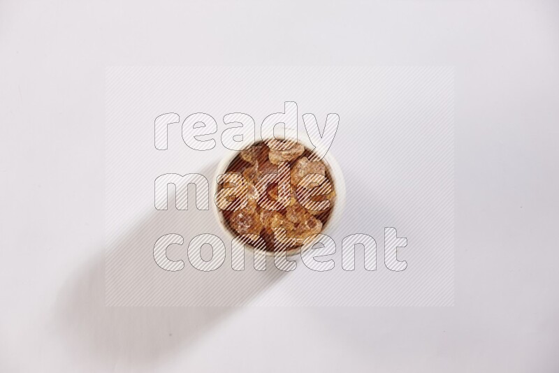 A beige pottery bowl full of gum arabic on white flooring