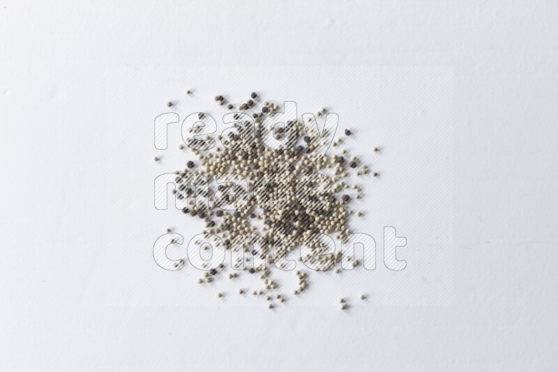 حبوب الفلفل المختلطة السوداء والبيضاء على أرضية بيضاء