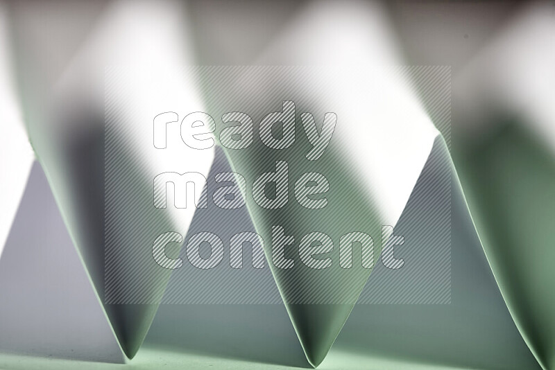 A close-up abstract image showing sharp geometric paper folds in white and green gradients