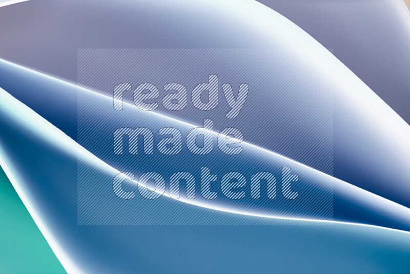 هذه الصورة تعرض تكوين فن الورق التجريدي مع منحنيات ورقية بتدرجات اللون الأخضر والأزرق المكونه بواسطة الضوء الملون