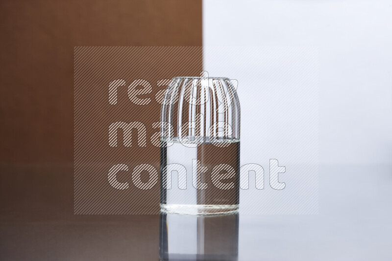 The image features a clear glassware filled with water, set against white and brown background