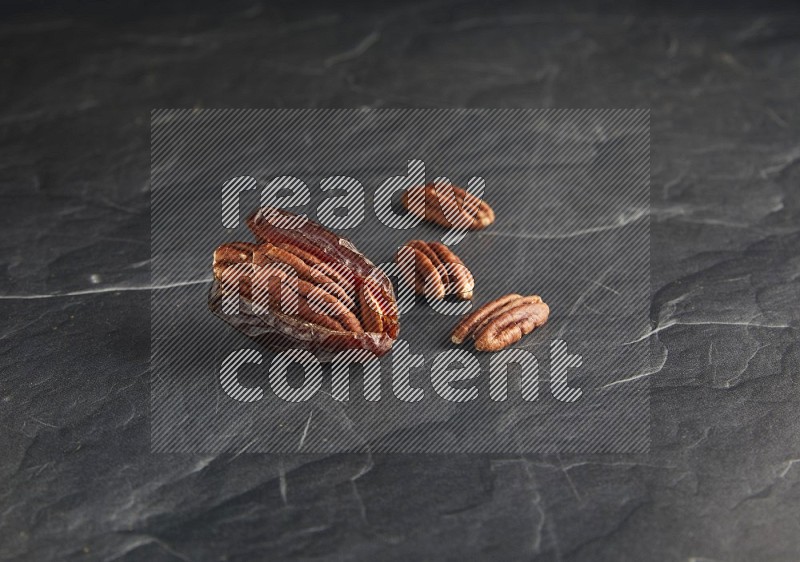 pecan stuffed madjoul date on a black textured background