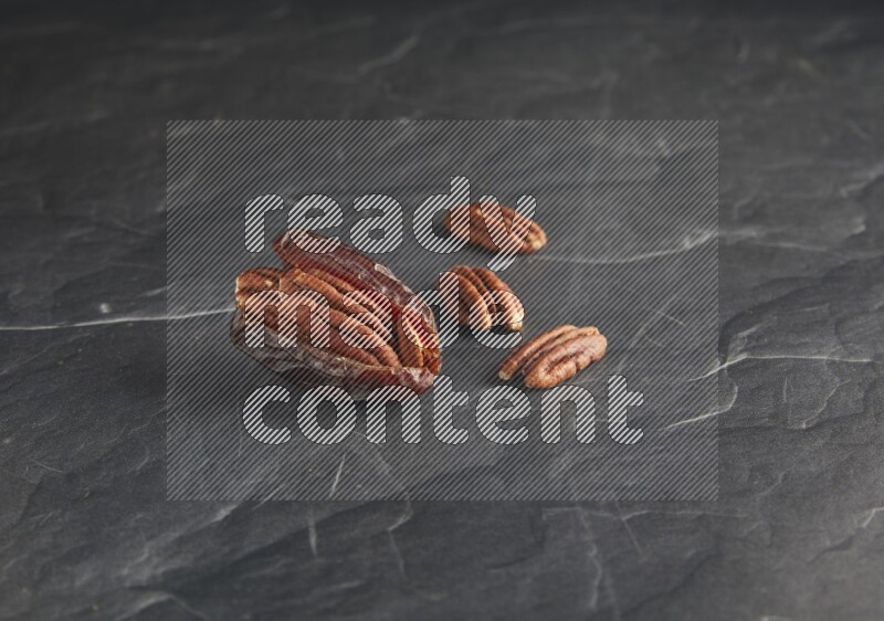 pecan stuffed madjoul date on a black textured background