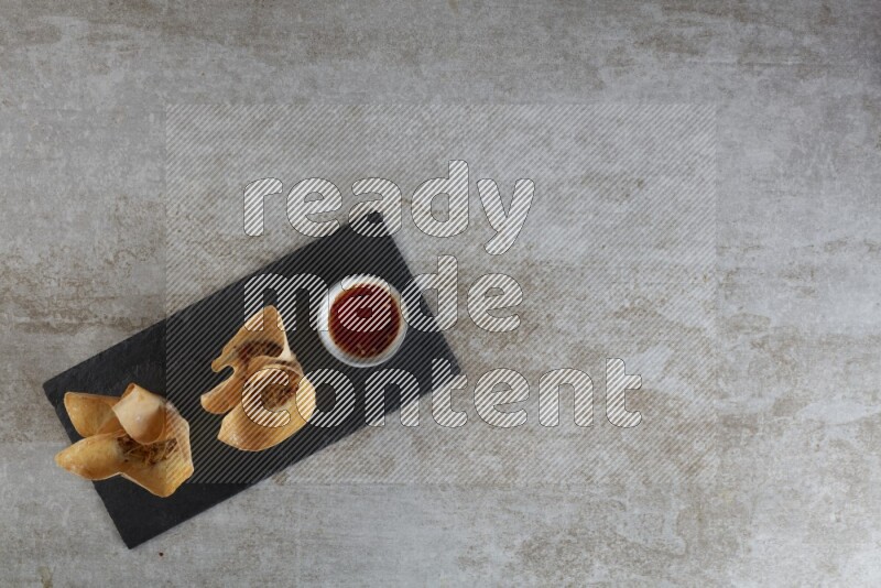 wonton cups with soy sauce ramkin on rectangle slate on grey textured counter top