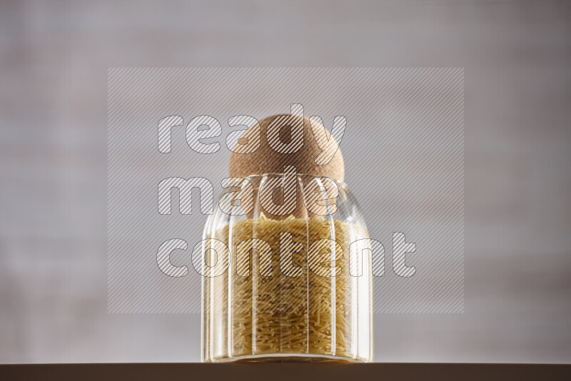 Raw pasta in glass jars on beige background