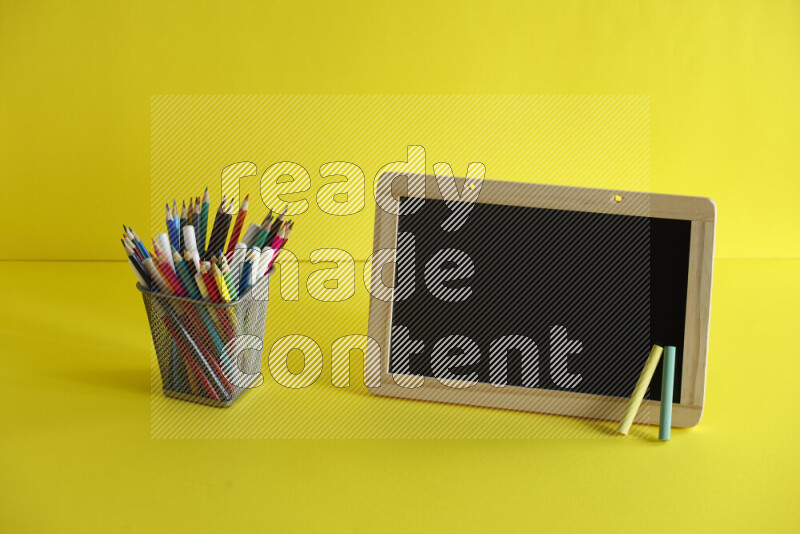 A blackboard with different school supplies on yellow background