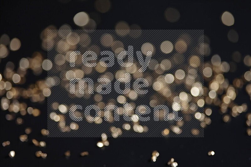 Gold shimmering fragments of glass scattered on a black background