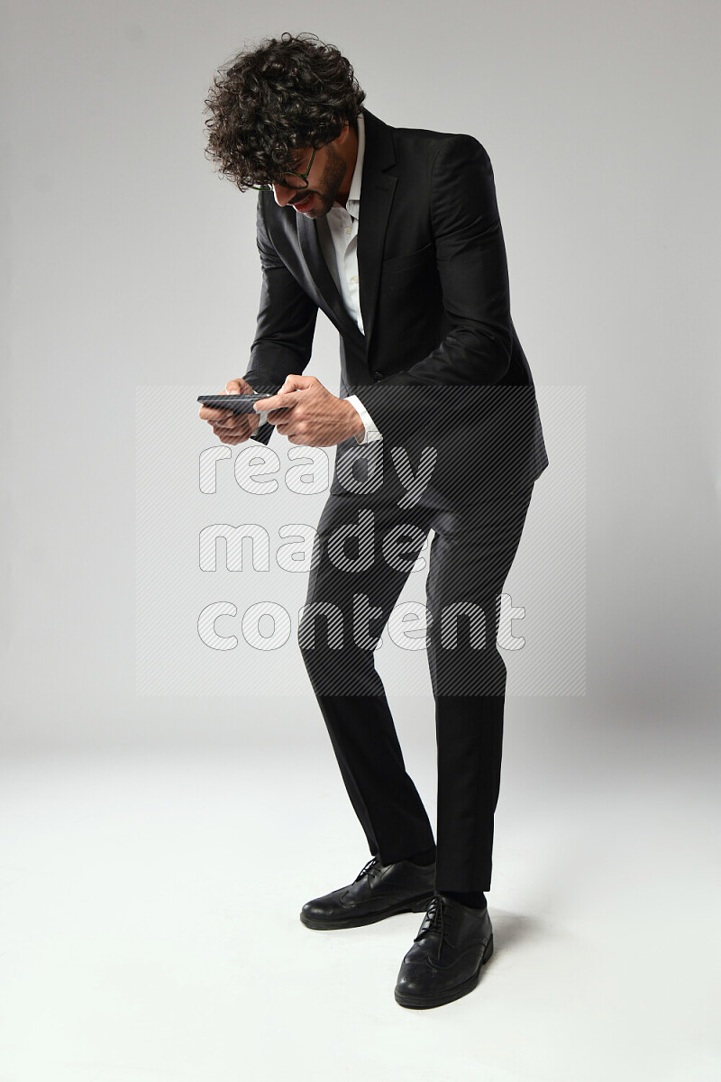 A man wearing formal standing and gaming on the phone on white background