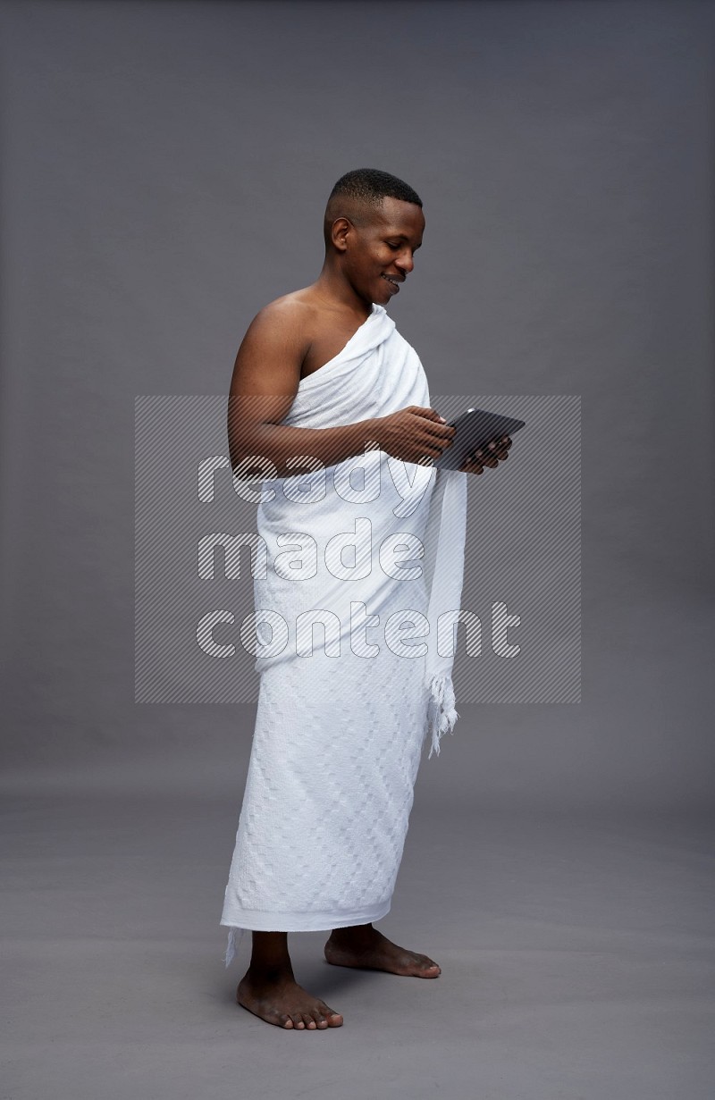 A man wearing Ehram Standing working on tablet on gray background