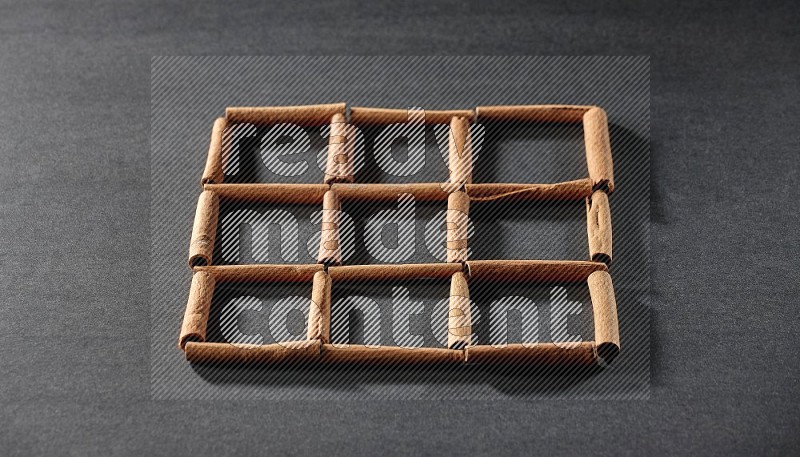 9 empty squares of cinnamon sticks on black flooring