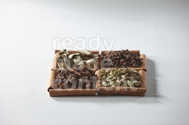 4 squares of cinnamon sticks full of cardamom, star anise, cloves and bay laurel leaves on white flooring