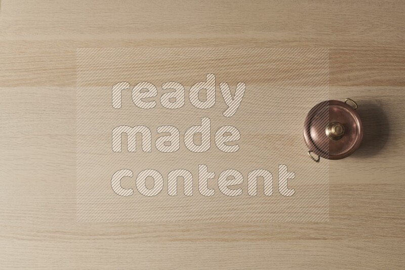 وعاء نحاسي صغير على خلفية خشبية فاتحة