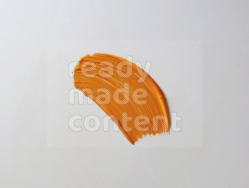 An orange curved painting brush stroke on a white background
