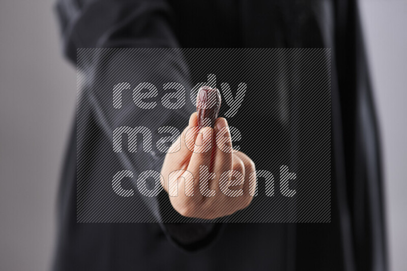 Woman in abaya holding dates in different positions