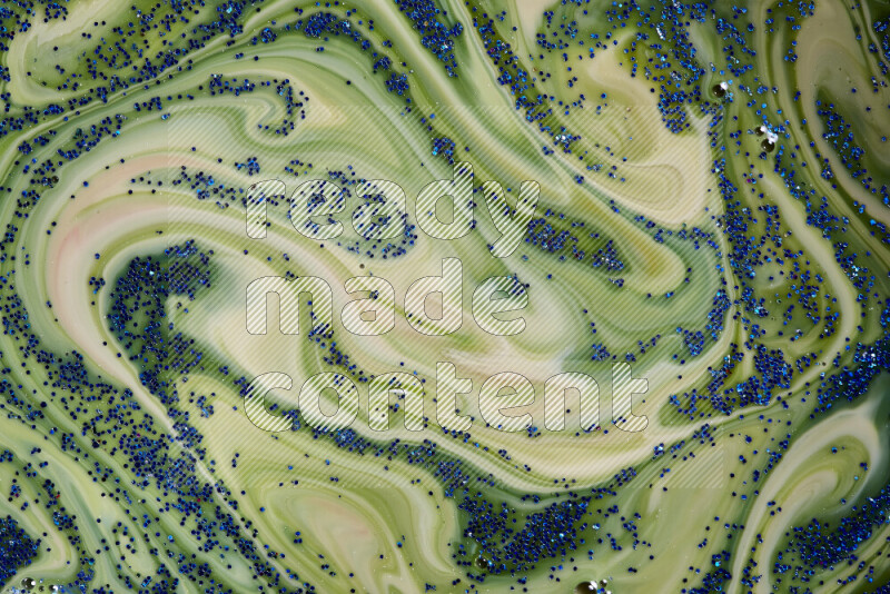 A close-up of sparkling blue glitter scattered on swirling blue and green background