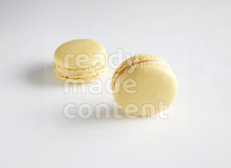 45º Shot of two Yellow Vanilla macarons on white background