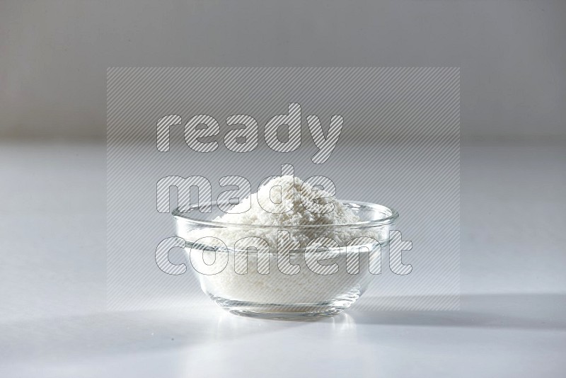 A glass bowl full of desiccated coconut on a white background in different angles